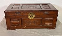 Front view of carved camphor wood chest showing brass latch and panel carvings