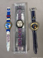 All three Swatch watches laid out: Thalassios, Award in box, Kranaos