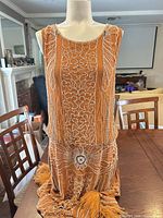 Front view of mustard flapper dress on mannequin showing beadwork and fringe hem