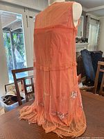 Full back view of coral beaded overlay dress on mannequin