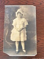 Front view of sepia portrait photograph showing young girl in dress and bonnet