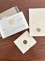 All items laid out: pin, medal in holder, letter, card, open box lid