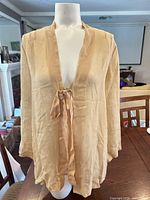 Front view of beige silk chiffon tie-front top on mannequin