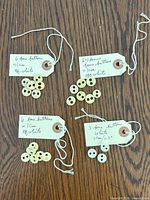 Four tagged groups of bone buttons displayed, handwritten tags noting quantities and size
