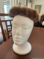 Front view of brown fur pillbox hat on mannequin head