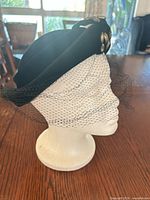 Left front view of black velvet cocktail hat showing veil and rhinestone cluster