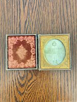Open case showing velvet pad and photograph with gilt mat