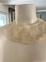 Front view of ivory lace collar on mannequin, showing floral lace pattern and overall condition