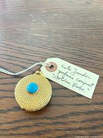 Closed compact with turquoise cabochon and tag