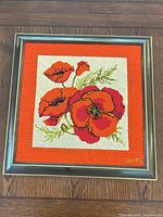Full view of framed needlepoint showing poppy design
