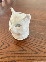Front angled view of ceramic cat coin bank showing glaze crazing and painted details