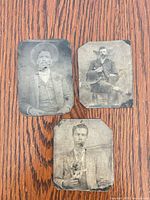 All three tintype photographs on wooden surface showing relative size and wear