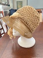 Left profile of tan cloche showing lattice overlay and ribbon brim