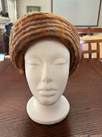 Front view of brown/tan striped faux fur cloche hat on mannequin head