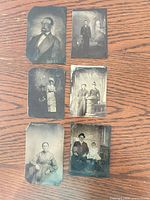Six tintype photographs arranged on wood surface