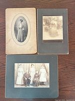 Three mounted cabinet card photographs displayed on table