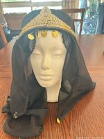 Front view on mannequin showing veil, gold trim, dangling discs