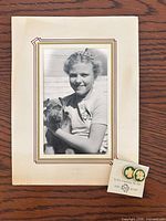 Mounted black & white photo of Girl Scout holding dog with pair of friendship pins on card