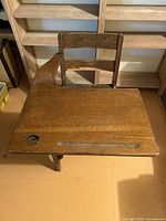 Top view of oak school desk showing inkwell hole, pencil groove, ladder-back chair