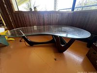 Full view of coffee table showing glass top and sculptural wood base