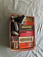 Box containing loose vacuum tubes and several boxed examples from Sylvania, RCA, GE and Realistic