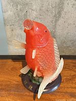 front view of translucent red-orange fish figurine on stand