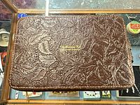 Closed view showing embossed floral cowhide exterior of zippered pouch
