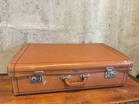 Front view of brown suitcase closed on table