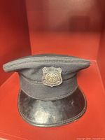 Front view of navy cap displaying badge and visor