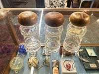Front view of the three identical clear glass spice jars with rounded wooden lids