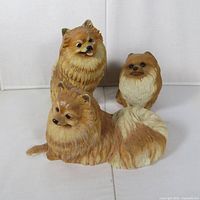 Front view of three resin Pomeranian dog figurines