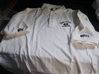 Full view of off-white Roots x Fort Henry polo showing chest and sleeve embroidery