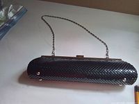 Full view of cylindrical black metal mesh clutch showing chain strap and base studs