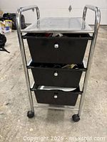Front view of chrome frame cart with three black drawers and casters