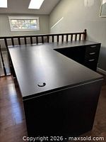 Overall top view of dark brown L-shaped desk showing surface and grommet