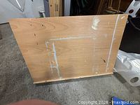 Front view of folding easel table showing light beech veneer panel with paint splatters and bottom ledge