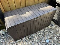 Front view of brown plastic deck storage box showing full rectangular form