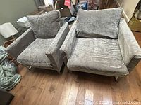 Front three-quarter view of both armchairs showing fabric and legs