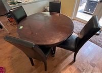 round wood dining table with four upholstered chairs around it