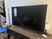Front view of Samsung TV powered off on console table with stand visible