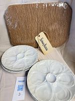Stack of six white porcelain oyster plates with Neiman Marcus retail tag visible