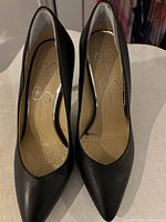 Front view of both black pumps showing pointed toes and insole branding