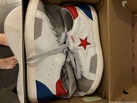 Both sneakers in box showing uppers and side star logo
