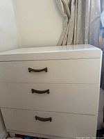 Front and left side view of white three-drawer dresser showing all drawers and handles