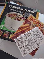Box of American Harvest Snackmaster Dehydrator 2400 with manuals and recipe book on top
