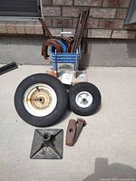 All items laid out: two wheels, cast base, tool heads, spike, bucket with rebar and hooks