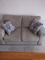Front view of beige loveseat with two decorative pillows