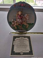 Front of raised-relief musical plate on stand with measuring tape and COA