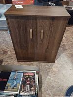 Front view of brown walnut veneer media cabinet, two doors with vertical handles