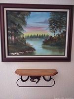 Wide view of framed painting above matching wall shelf